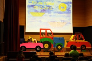 Escenario del Salón de Actos del CRE en el que aparecen los alumnos representando una obra teatral disfrazados como coches de cartón