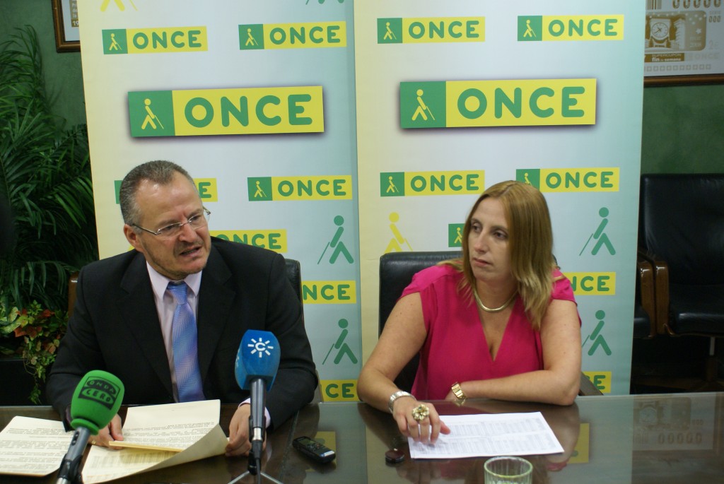 El delegado territorial de la ONCE en Andalucía, Ceuta y Melilla, Patricio Cárceles, junto a la directora de la ONCE Córdoba, Estela Medina, enseñando el libro de la memoria