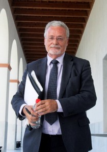 En la imagen, plano medio del Defensor del Pueblo Andaluz en el que aparece con una carpeta y una botella de agua mirando a cámara