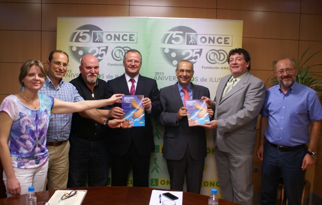 Foto de familia en la que los trabajadores de ONCE Sevilla muestran a cámara los libros sobre la memoria económica y social