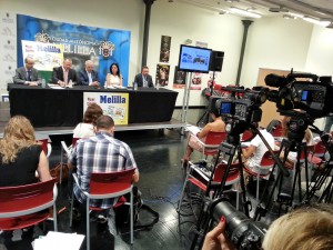 En la imagen, de fondo, la mesa de presidencia y, frente a ellos, las cámaras de televisión, durante la presentación de los cupones dedicados a Melilla