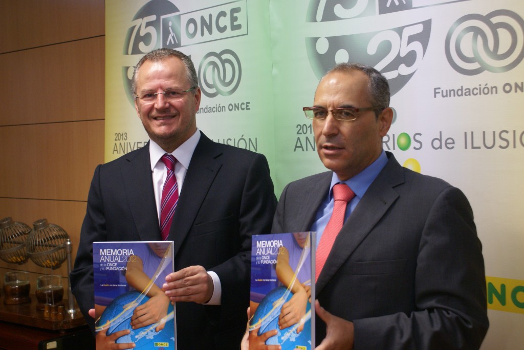 El delegado territorial de la ONCE en Andalucía, Ceuta y Melilla, Patricio Cárceles, junto al subdelegado territorial, Francisco Arroyo, enseñando el libro de la memoria