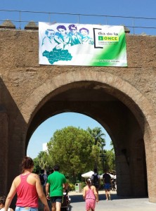 En la imagen, varias personas pasan por debajo de un puente decorado con una pancarta con la inscripción: "Día de la ONCE. La ilusión nos une"