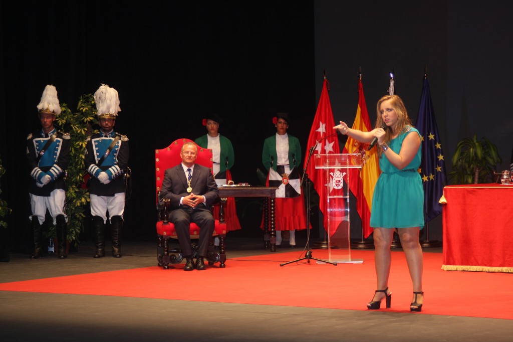 Coraluna canta uno de sus temas en el escenario. Tras ella, Patricio Cárceles sentado tras recoger la Medalla