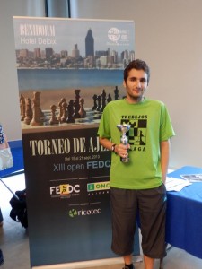 En la imagen, Fernando Escalante mira a cámara posando junto a su trofeo. Tras él, el cartel conmemorativo del torneo