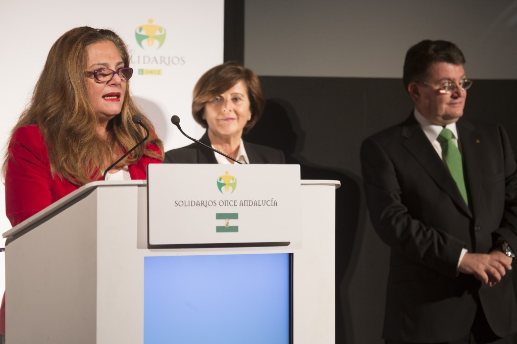 En el atril, aparece hablando Pilar Vergara. De fondo, María José Sánchez y Ángel Sánchez