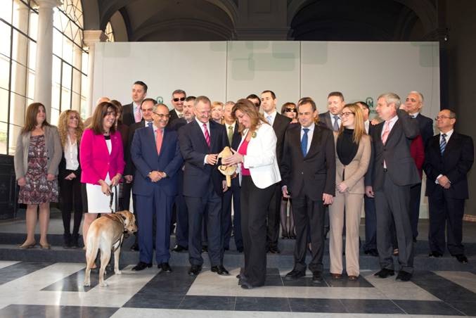 El delegado territorial de la ONCE en Andalucía, Ceuta y Melilla, Patricio Cárceles, le entrega un peluche de un perro guía a la Presidenta de la Junta de Andalucía, Susana Díaz