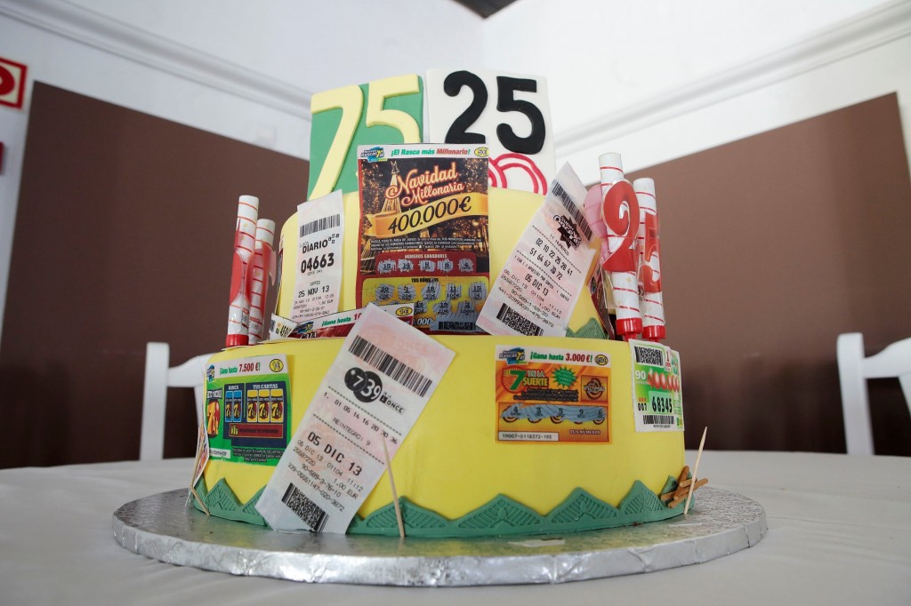La tarta está llenas de detalles. Cupones pegados, rasca, figuras de vendedor y dos números el 75 y el 25 