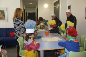 Un grupo de niños se distribuye alrededor de una mesa mientras preparan una receta