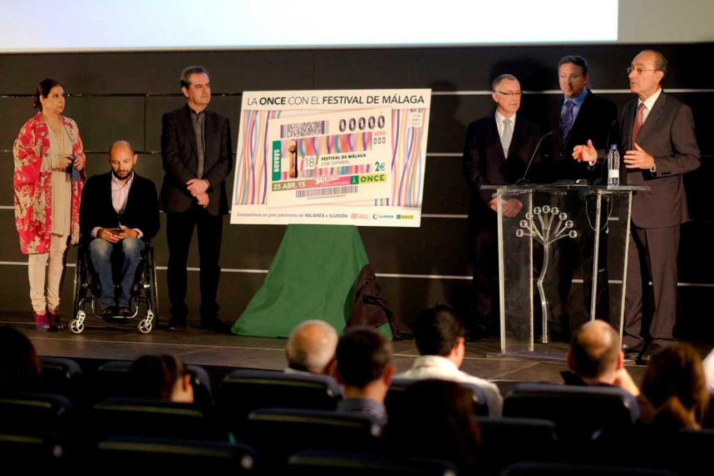 El alcalde de Málaga en el atril durante un momento de su discurso junto a los organizadores del festival, el delegado territorial de la ONCE y miembros de la agrupación teatral El Malecón