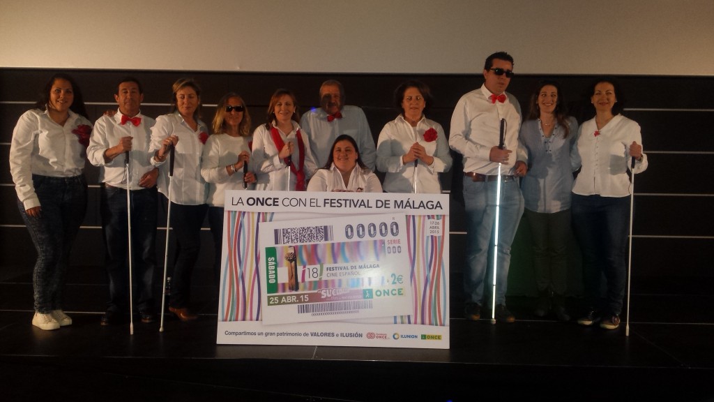 Foto de familia del grupo de teatro malagueño "El Malecón" junto a la reproducción del cupón