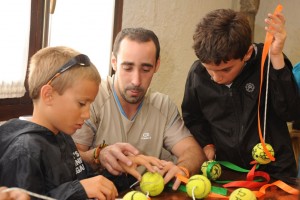 Dos niños ciegos confeccionan un móvil con pelotas de tenis usadas junto a uno de sus monitores