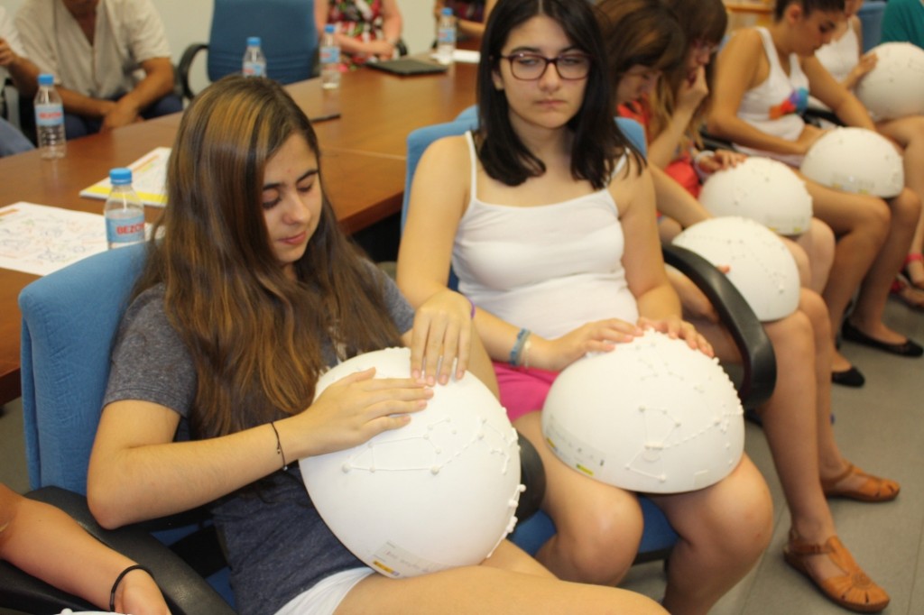 Un grupo de niños toca una reproducción en relieve de las constelaciones del hemisferio norte