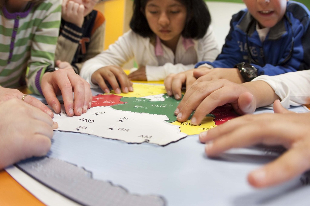 Detalle de manos de alumnos sobre el mapa en relieve de España 