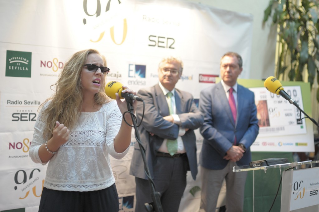 Coraluna micrófono en mano cantando su canción ante la atenta mirada del alcalde de Sevilla y del director general de la SER en Andalucía