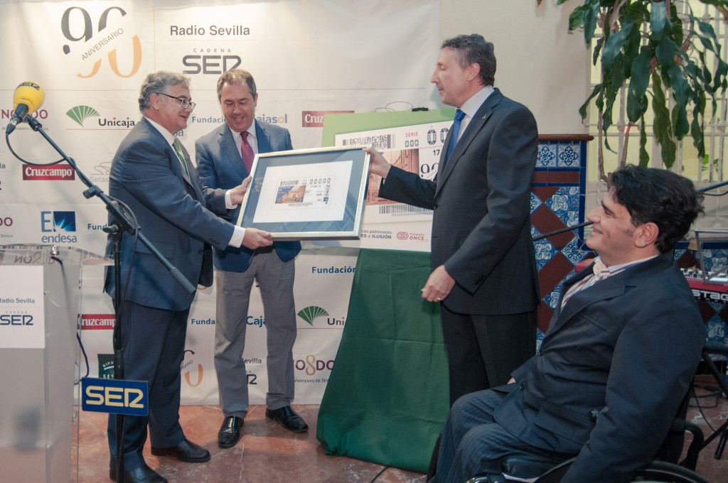 El delegado territorial entrega el cupón enmarcado al director general de la SER en Andalucía ante los aplausos del resto de autoridades