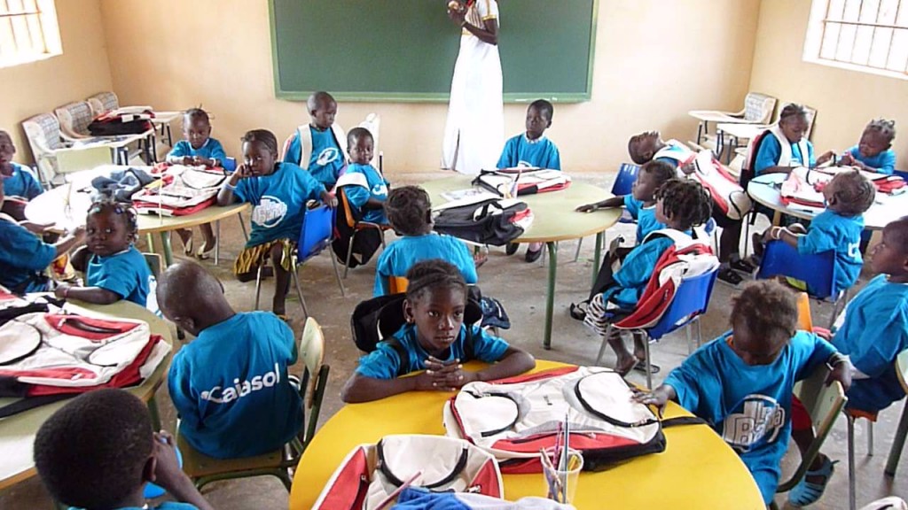 Niños guineanos sentados con las mochilas de la ONCE en la escuela construida por la APS