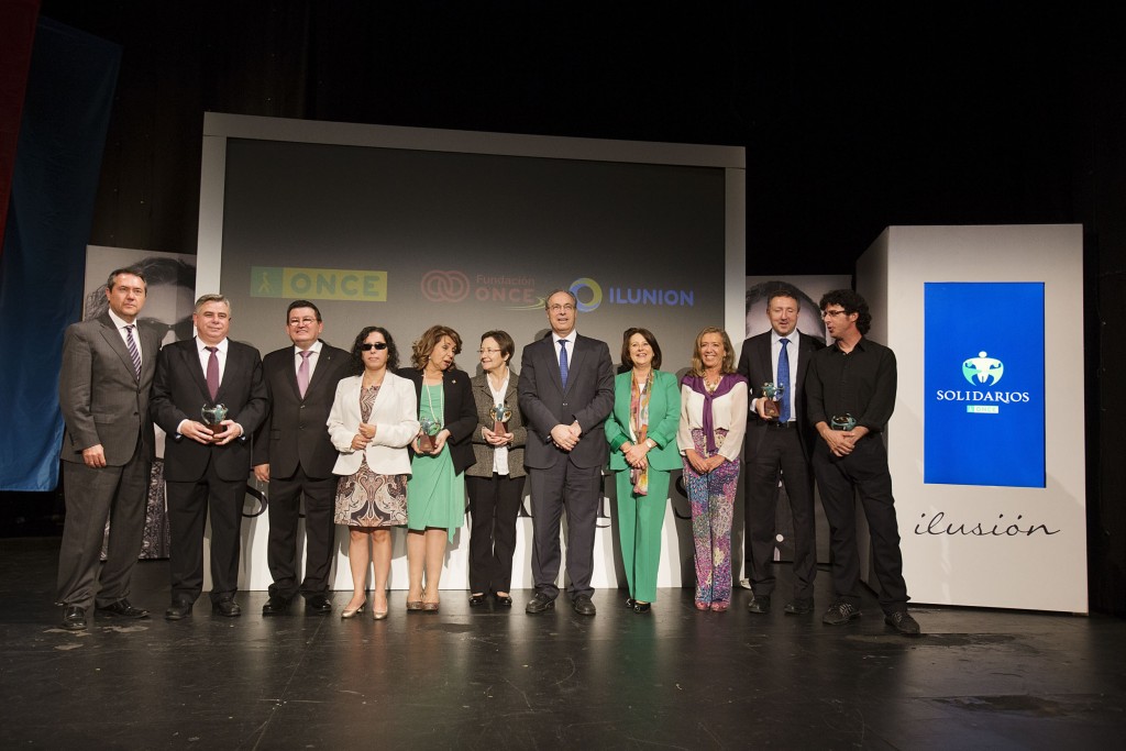 Foto de familia de autoridades con premiados en el escenario tras el acto.