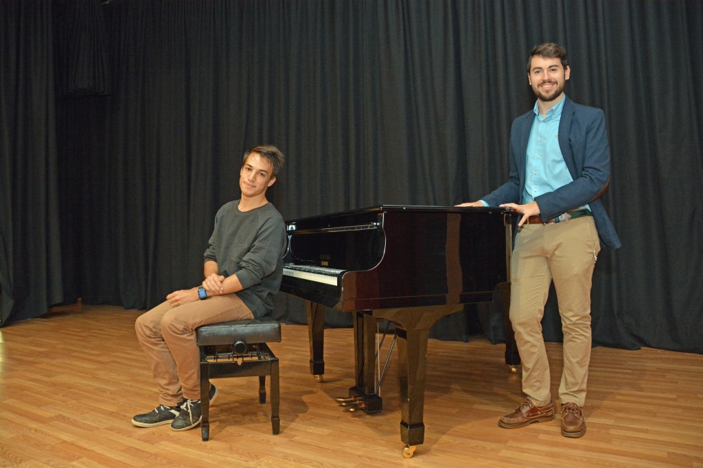 A la izquierda, Víctor Goméz, pianista sentado sobre en el sillón del piano. A su derecha, Álvaro Bernal, de pie junto al piano. 