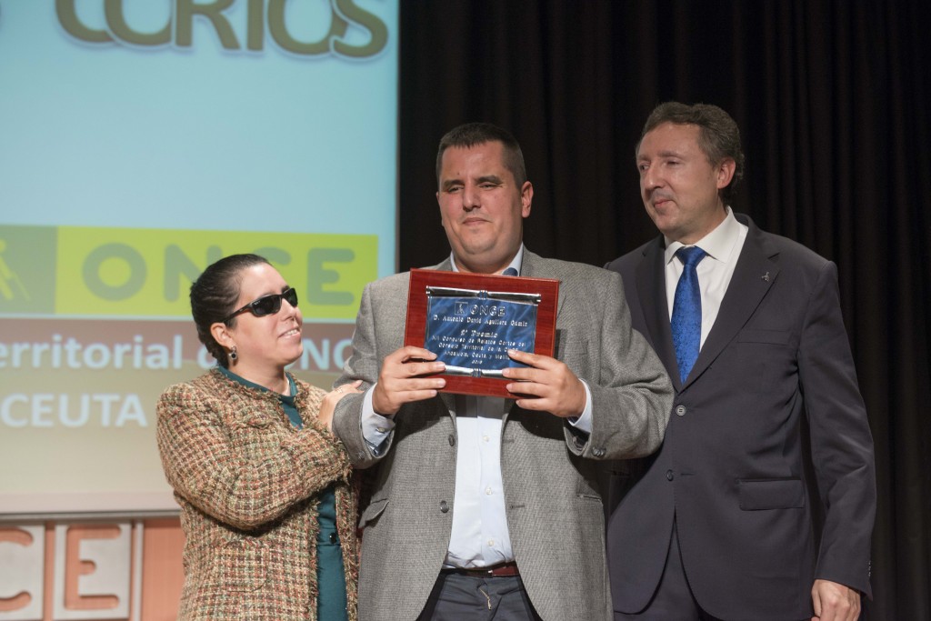 A la izquierda, Isabel Viruet, presidenta del Consejo Territorial de la ONCE en Andalucía. A la derecha, Cristóbal Martínez, delegado territorial de la ONCE en Andalucía, entregan el galardón a David Gámiz, ganador del segundo premio en el Concurso de Relatos Cortos