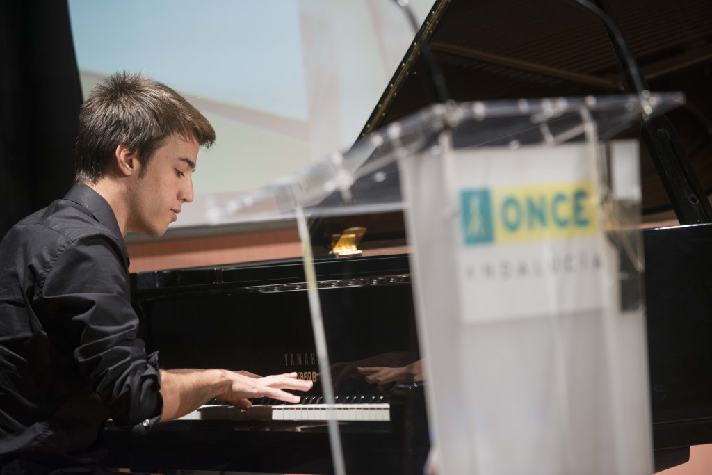 Primer plano de Víctor Gómez, pianista afiliado. Aparece tocando el piano durante su actuación en la entrega de premios del Concurso de Relatos Cortos y Habilidades Artísticas 