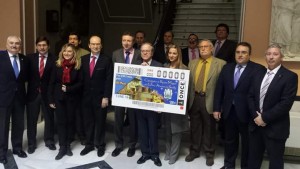 Foto familia durante el acto de presentación del cupón dedicado a la Cabalgata de Reyes del Ateneo de Sevilla. Aparecen mostrando la imagen del cupón 
