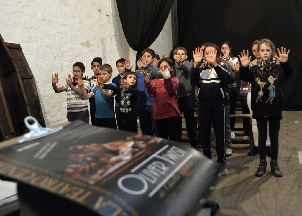 Primer plano del cartel del Musical con los niños al fondo en el ensayo.