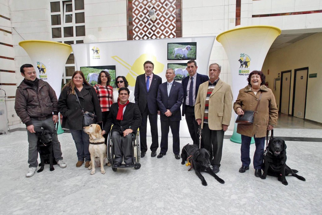 Foto de familia de los intervinientes en la inauguración junto a usuarios de perros guía