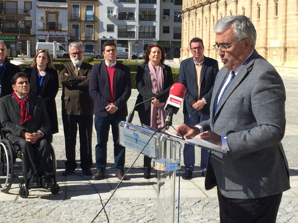 Primer plano del consejero con los portavoces parlamentarios al fondo de la imagen