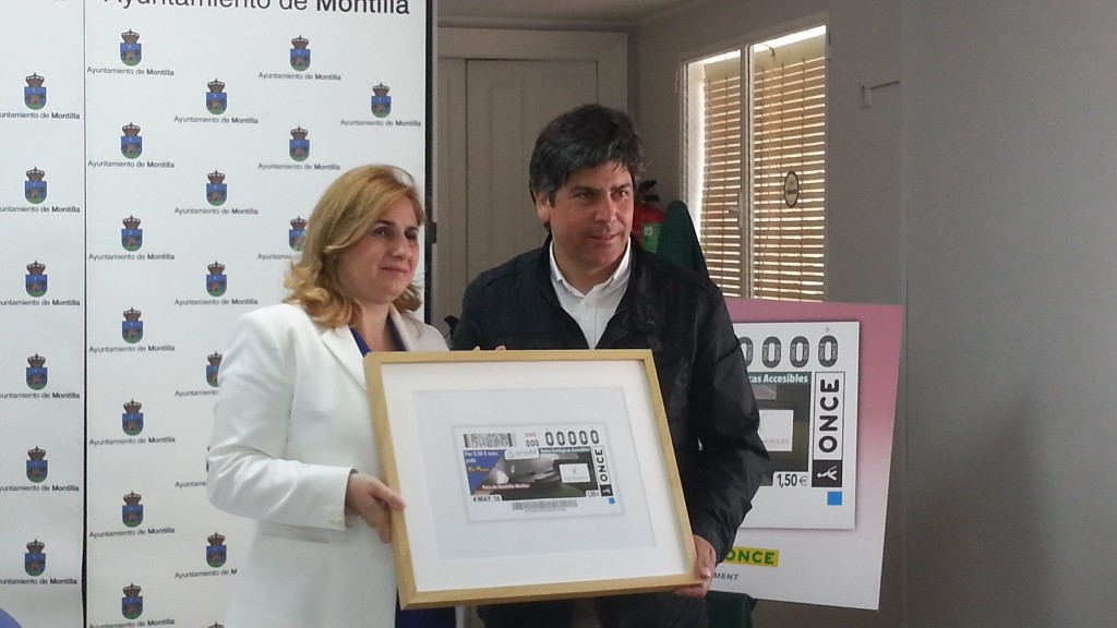 Posado gráfico de Carmen Aguilera con el alcalde de Montilla sosteniendo la imagen del cupón