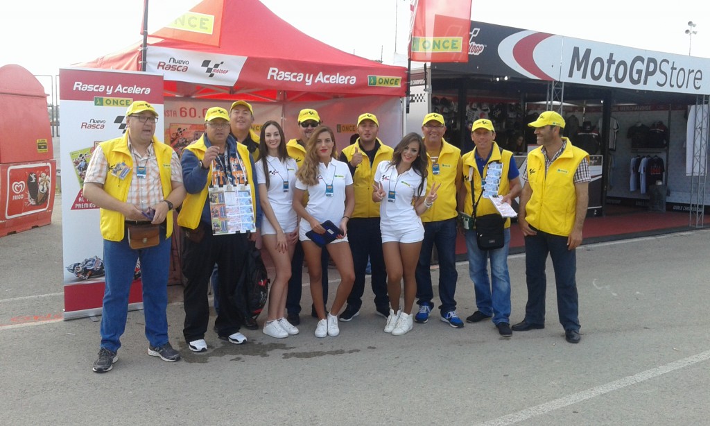 Los vendedores de la ONCE aparecen acompañados por tres voluntarias contratadas por el circuito posan en conjunto para las cámaras con la carpa diseñada para la ocasión a sus espaldas