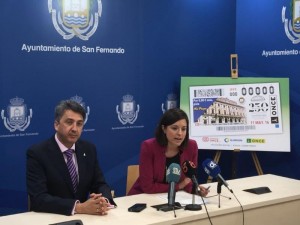 Presentación del cupón en honor a la localidad gaditana de San Fernando en su 250 aniversario, con la imagen del mismo de fondo en el Ayuntamiento del pueblo.