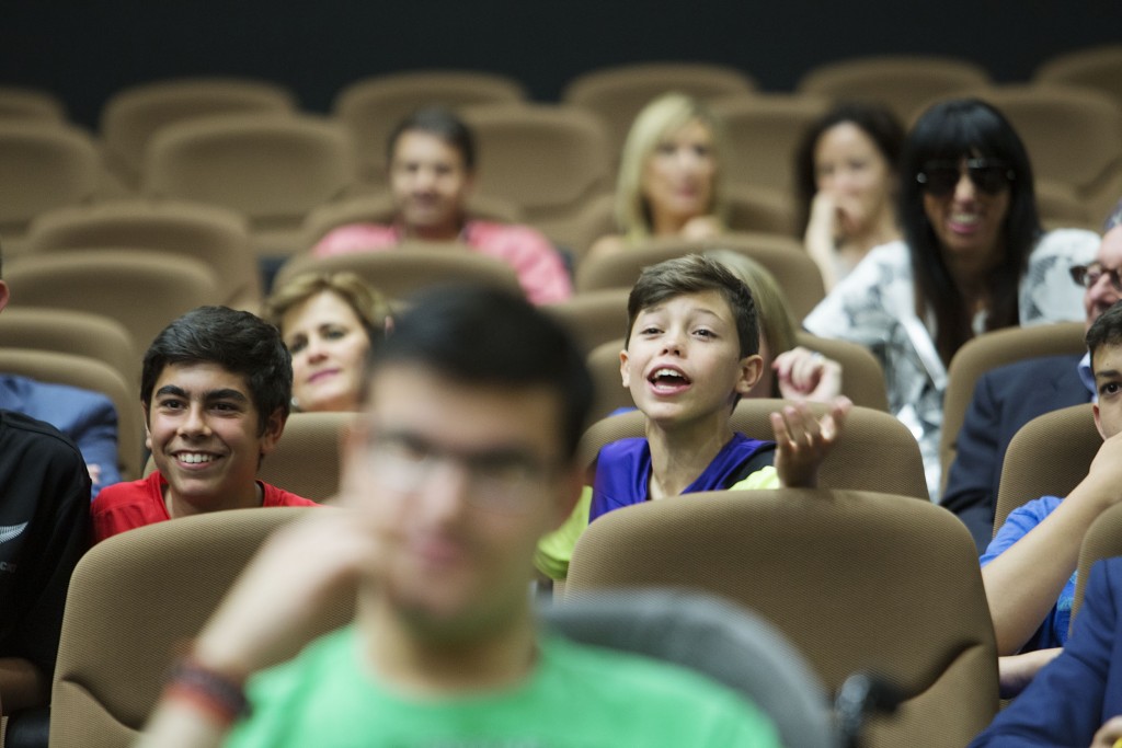 Dos alumnos muy sonrientes desde el público hablando con su interlocutora en el escenario