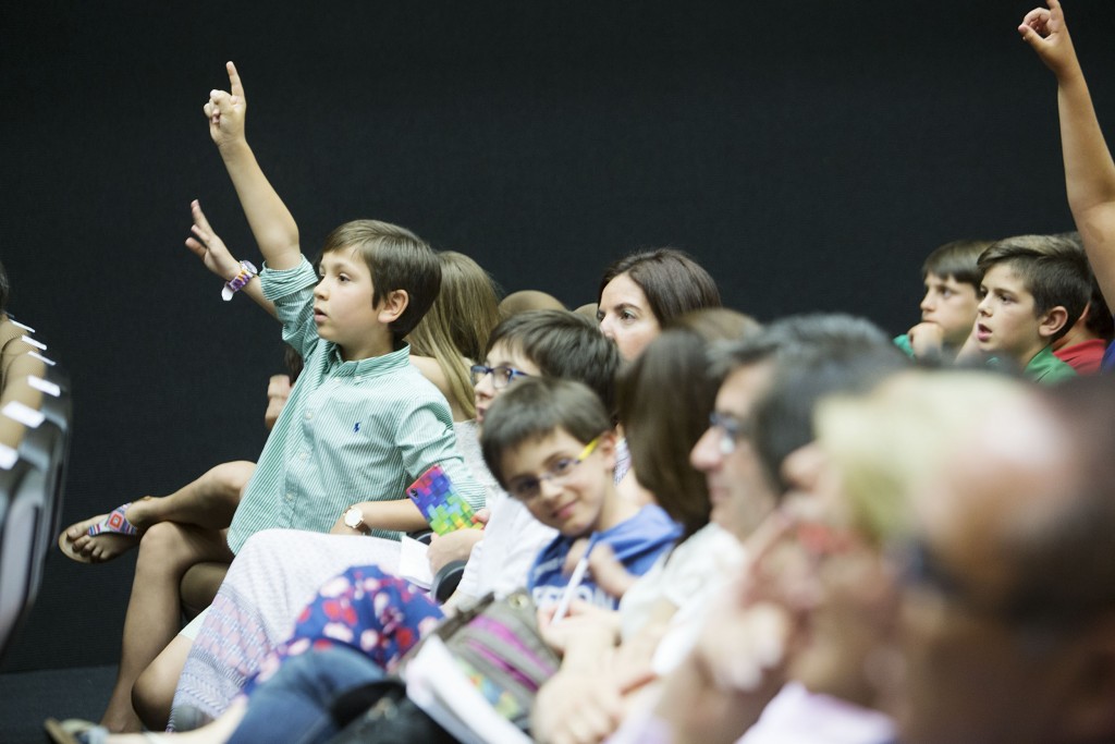 Un alumno con el dedo levantando esperando a que le toque el turno para dar su respuesta