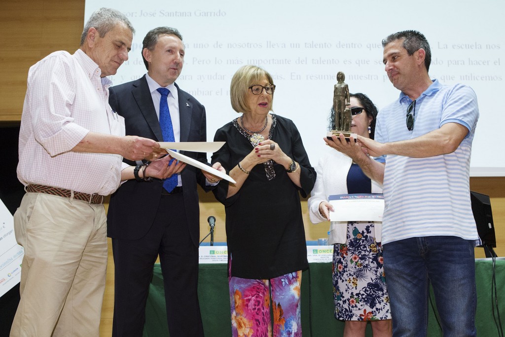 Un profesor del centro recibe sonriente la escultura de un usuario con perro guía