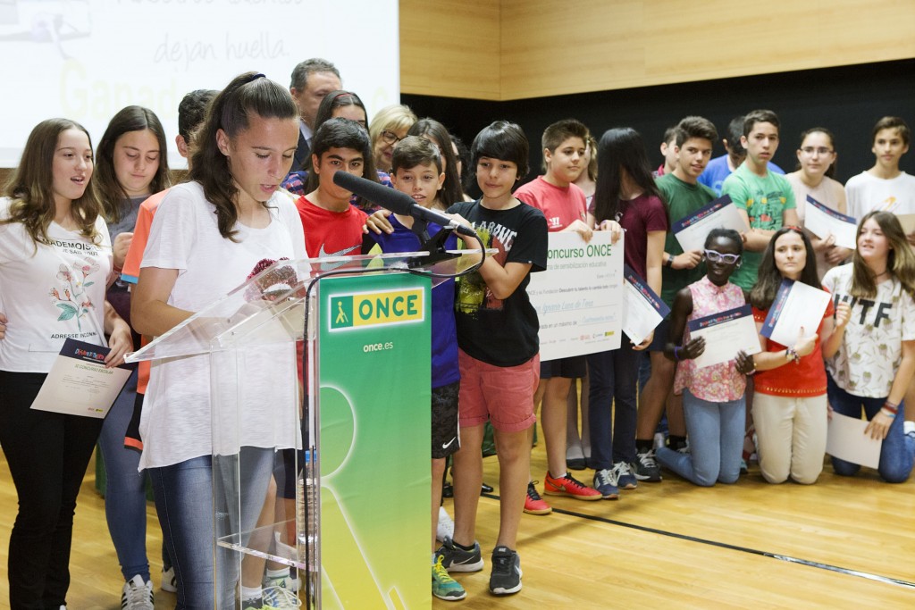 Alumna acompañada de sus compañeros de clase en el escenario leyendo la Declaración por el Fomento del Talento