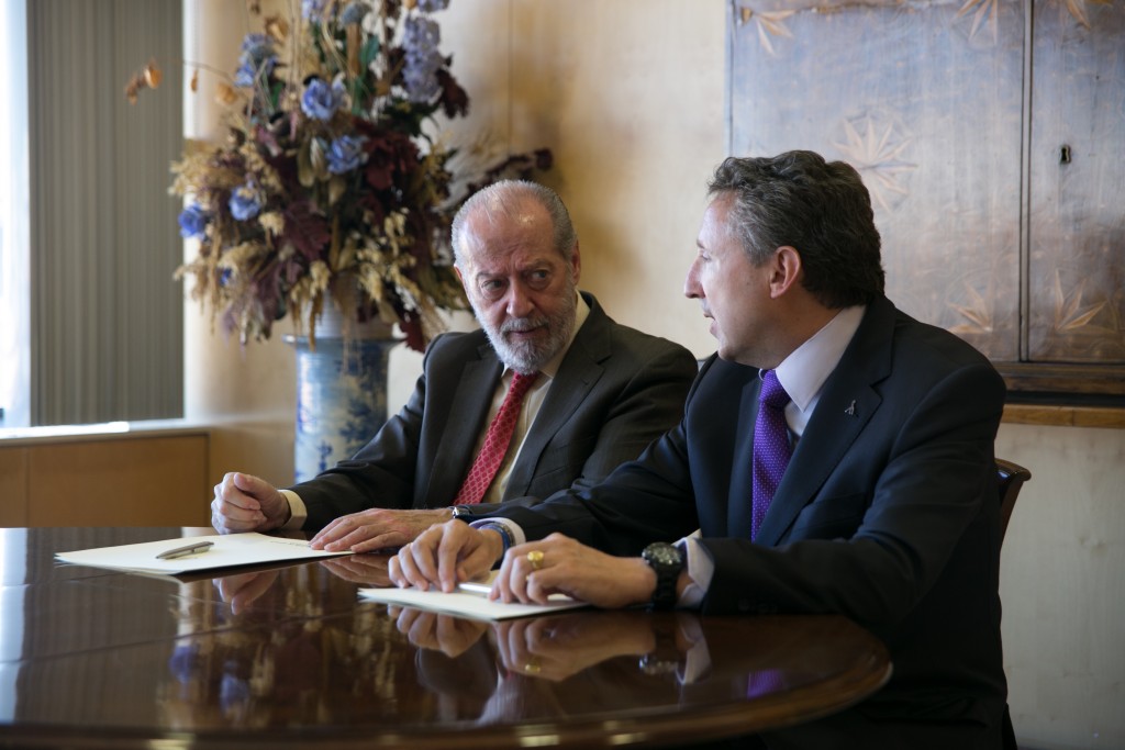 El presidente de la Diputación de Sevilla mira atento al delegado territorial durante su intervención tras la firma