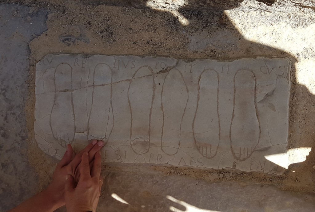 Unas manos perciben la silueta de unas huellas griegas