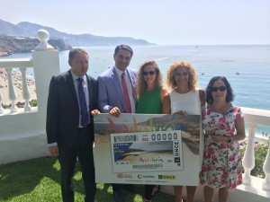Los participantes sostienen la imagen del cupón desde la terraza del parador de Nerja con la costa del Sol de fondo
