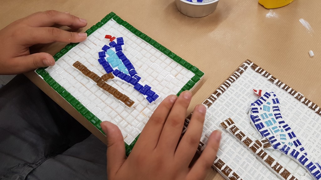 Unas manos trabajando sobre uno de los mosaicos que se hicieron en el taller