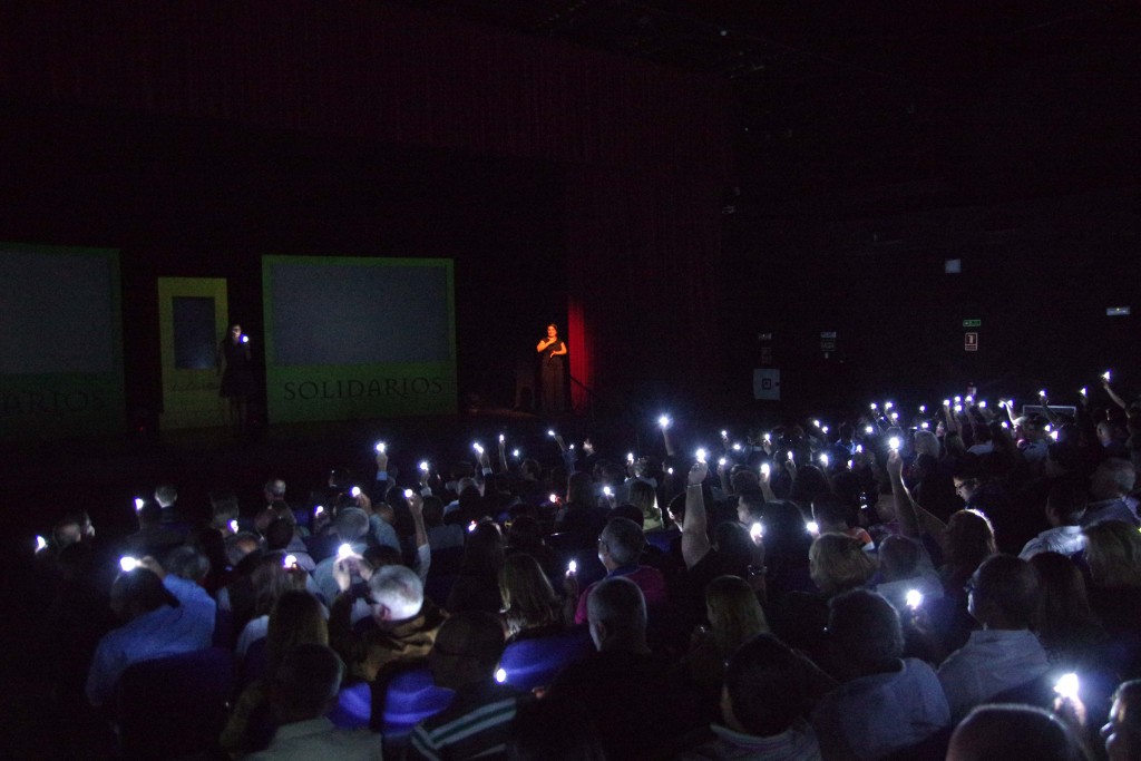 el público con las luces apagadas y encendiendo sus bombillas