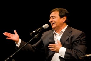 Calixto Sánchdz con una mano en el pecho y otra extendida con los ojos cerrados cantando