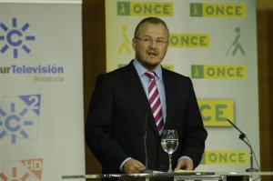 Patricio Cárceles en un momento de su intervención con los logos detrás de la ONCE y Canal Sur TV