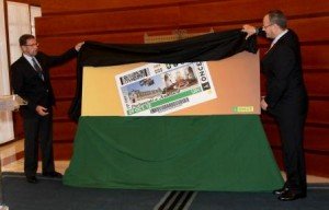 El delegado territorial de la ONCE en Andalucía, Ceuta y Melilla, Patricio Cárceles, destapa la imagen del cupón con la ayuda del presidente de la Mesa del Parlamento, Manuel Gracia